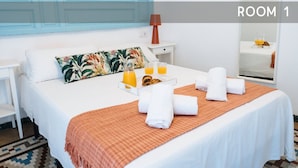A neatly made bed with towels, a tray of orange juice, and a breakfast setting in a room with a checkered floor and a white bedspread. - Andalusian Flavour in Heart of Seville 4´giralda (Sevilla)