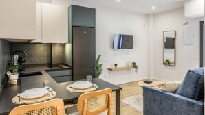 A modern kitchen with a dining area, a flat-screen TV, and a sofa. - Luxe Apartments Madrid Rio by Rentitup (Madrid)