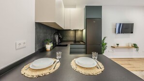A modern kitchen with dark countertops, white cabinets, and a built-in oven. There is a small island with a sink and a potted plant. - Luxe Apartments Madrid Rio by Rentitup (Madrid)