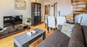 Un salon comprenant un téléviseur, un canapé, une table basse, un meuble et un coin repas avec des chaises et une table.