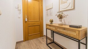 A wooden door, a desk with a globe, a vase with dried flowers, and a framed picture on the wall.