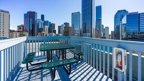 A rooftop terrace with a table and benches, overlooking a city skyline with modern buildings. - Downtown Studio with King Bed & City Views (Seattle)