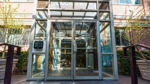 A modern building entrance with glass doors and a keypad security system. - Downtown Studio with King Bed & City Views (Seattle)
