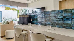 Una cocina moderna con cubierta blanca, dos taburetes de bar y salpicadero con azulejos azules.