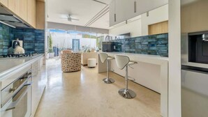 Una cocina moderna con una isla central, taburetes de bar y vistas al exterior.
