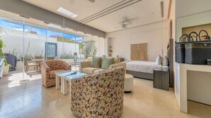 Una sala de estar moderna con sofá, una mesa de centro, cama y mueble para televisión.