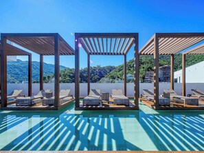 A rooftop pool area with sun loungers and a pergola structure.
