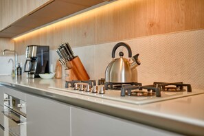A modern kitchen with stainless steel appliances, a kettle, and a knife set on the counter. - NEW Custom Luxury Condo in SOHO PV - Best Rooftop (Puerto Vallarta)