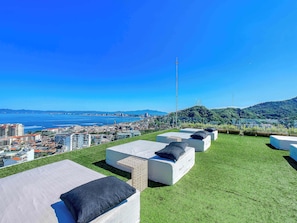 A rooftop lounge area with outdoor seating and a view of the city and coastline. - NEW Custom Luxury Condo in SOHO PV - Best Rooftop (Puerto Vallarta)