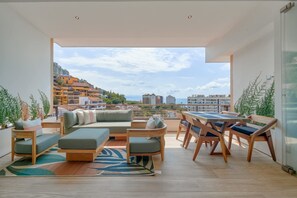 A modern balcony with a sofa, chairs, and a dining table.