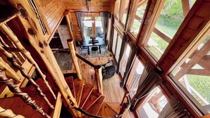 Un escalier en colimaçon avec des finitions en bois, menant à un espace repas comprenant une table et des chaises.