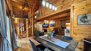 L’intérieur d’une cabane en bois comprend un coin repas, une cuisine, un salon et un escalier menant à une mezzanine.