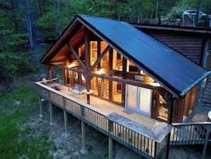 A log cabin with a deck, large windows, and a fire pit. - Spirit Lake Manor | Private | Hot Tub | RRG (Rogers)