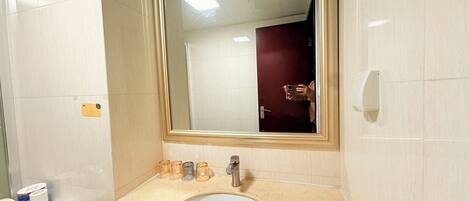 Un baño con lavamanos blanco, espejo y retrete.