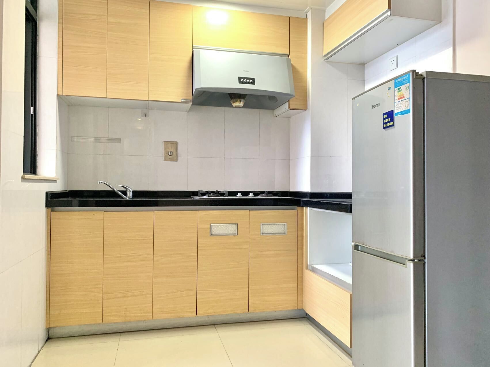 Una cocina moderna con armarios de madera, un refrigerador de acero inoxidable y una encimera negra.