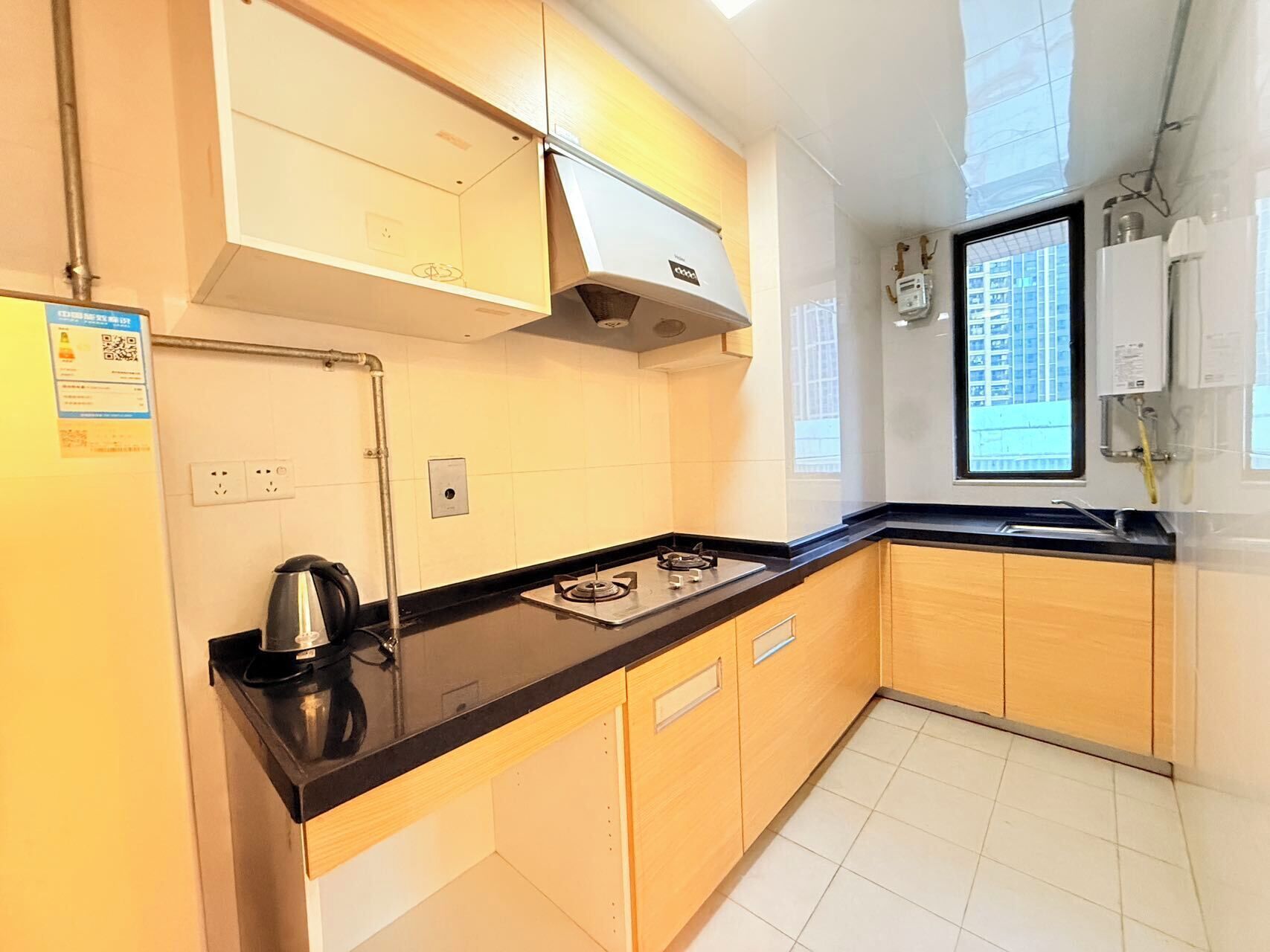 Cocina moderna con armarios de madera, encimera negra y estufa integrada. Una ventana ofrece luz natural y vistas al exterior.