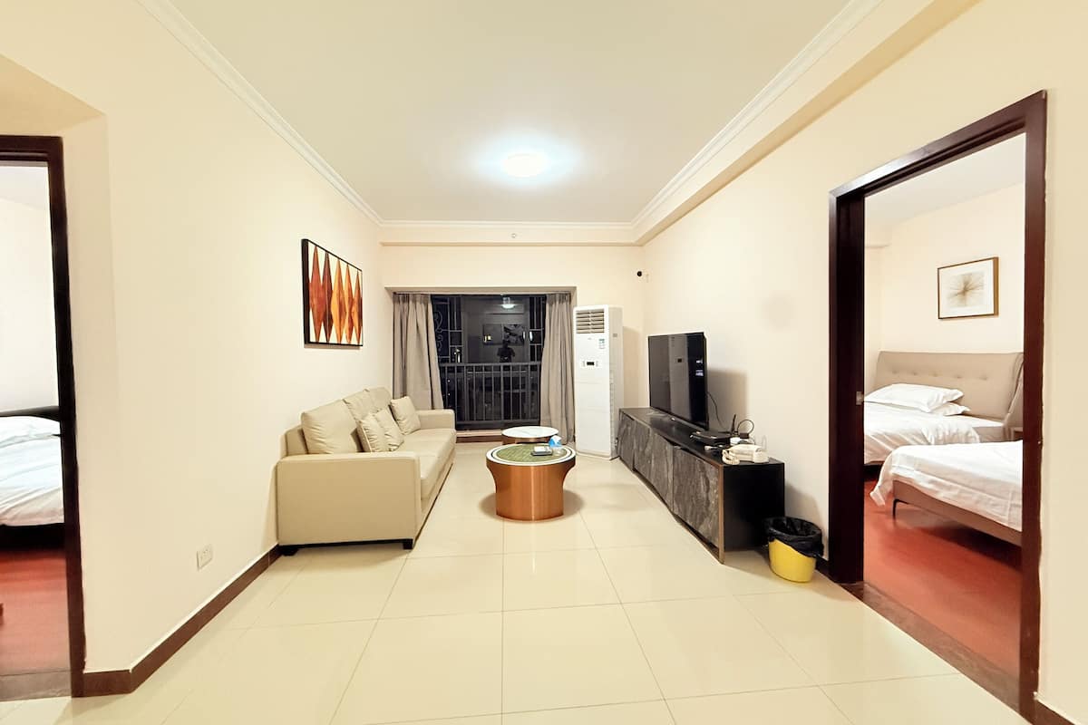 A hotel room with a sofa, a TV, a minibar, and a bed.