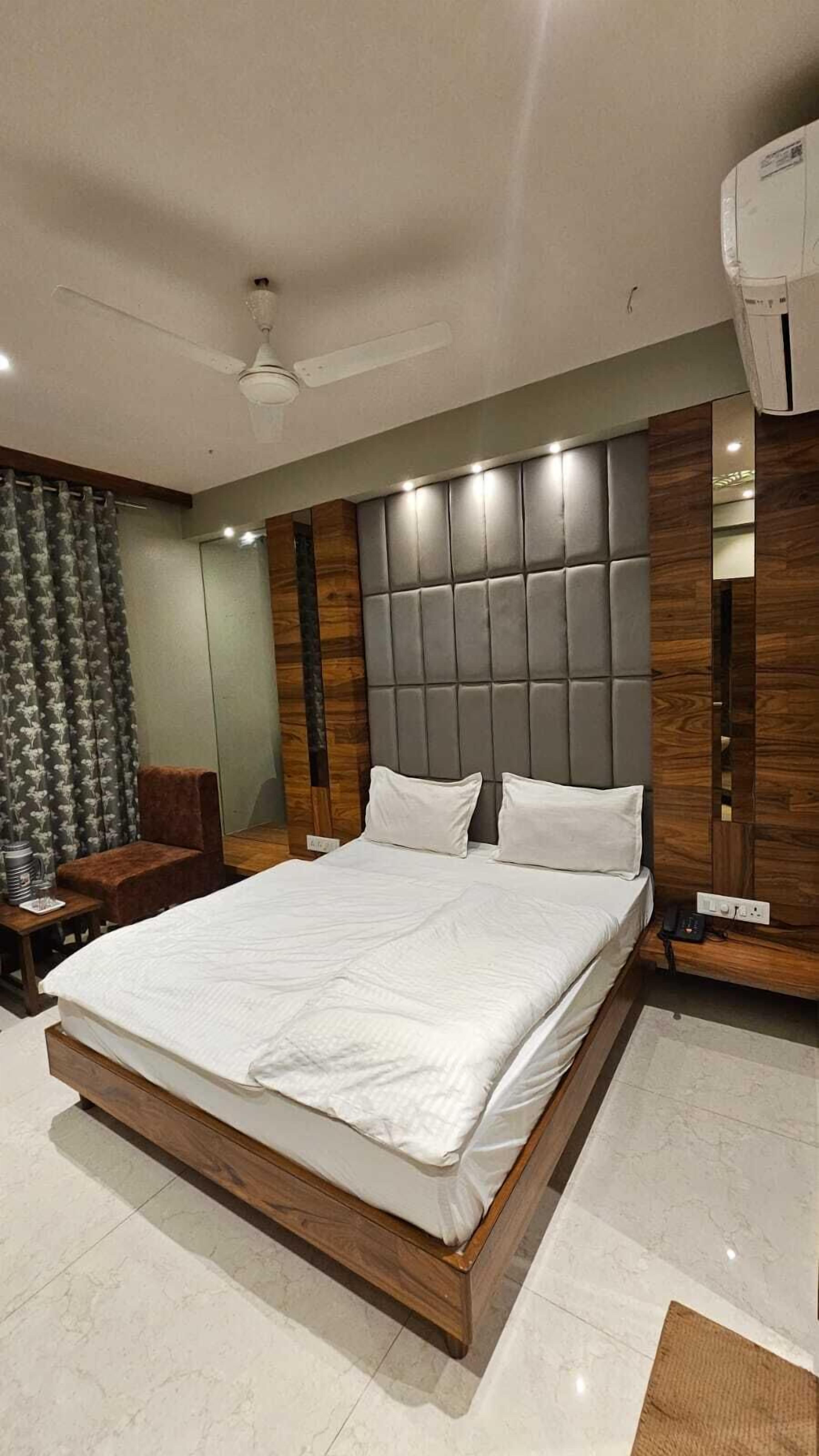 Quarto moderno com cama grande, cabeceira de madeira e ventilador de teto.