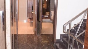 Eine moderne Hotelhalle mit Marmorboden, einer Treppe mit Metallgeländern und einem Glaselevator.