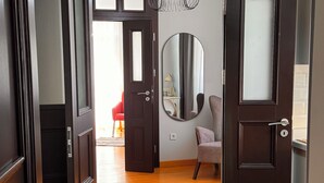 A hallway with wooden flooring, a large mirror, and a red chair. - İstanbul Guesthouse (Istanbul)