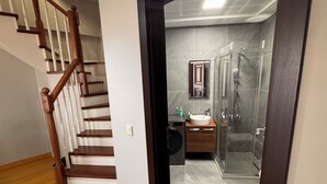A modern bathroom with a glass shower enclosure, a built-in sink, and a mirror above the sink. - İstanbul Guesthouse (Istanbul)