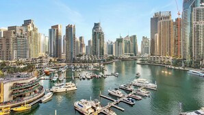 A marina with multiple boats docked, surrounded by high-rise buildings and a clear sky.