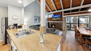 A modern kitchen with granite countertops, a built-in oven, and a stone fireplace.
