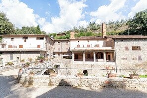 A traditional stone building with a courtyard, a small bridge, and potted plants. - Exclusive Resort W/ Pool & Waterfall - A11 (Loro Ciuffenna)