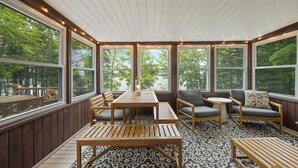 Un espace extérieur aménagé avec des meubles en bois, de grandes fenêtres et un sol à motifs, le tout abrité.