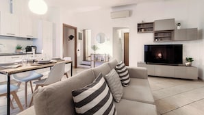 En moderne stue med sofa, fjernsyn og spiseplads.