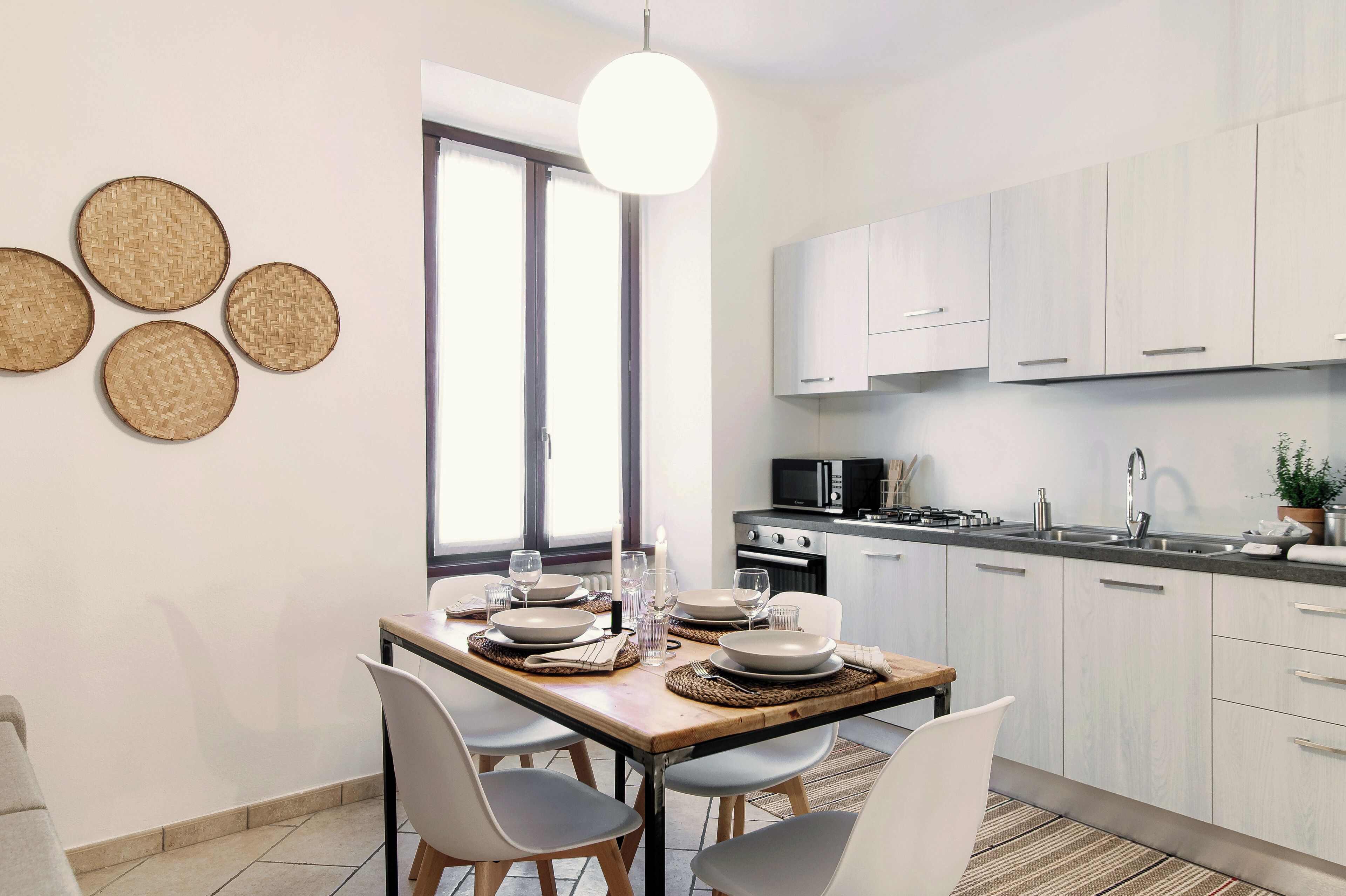 A modern kitchen with light-colored cabinets, a stainless steel sink, and a microwave.