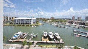 Un port de plaisance avec des bateaux amarrés, un grand bâtiment doté d’un toit blanc et un ciel bleu dégagé.