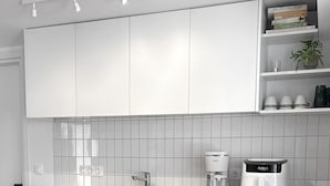A modern kitchen with white cabinets, a wooden countertop, and a dining area with a table set for two.