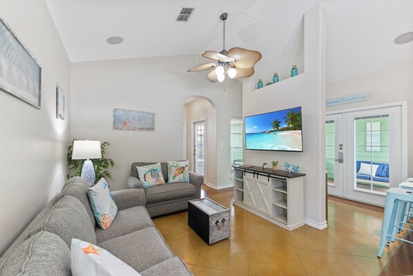 A living room with a grey sofa, a coffee table, a TV, and a ceiling fan.