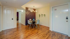 Comedor con piso de madera, una mesa redonda con cuatro sillas, una lámpara moderna y una puerta con letrero de advertencia de seguridad.
