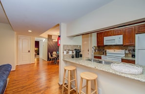 Una cocina moderna con armarios de madera, un lavamanos de acero inoxidable y un microondas integrado.