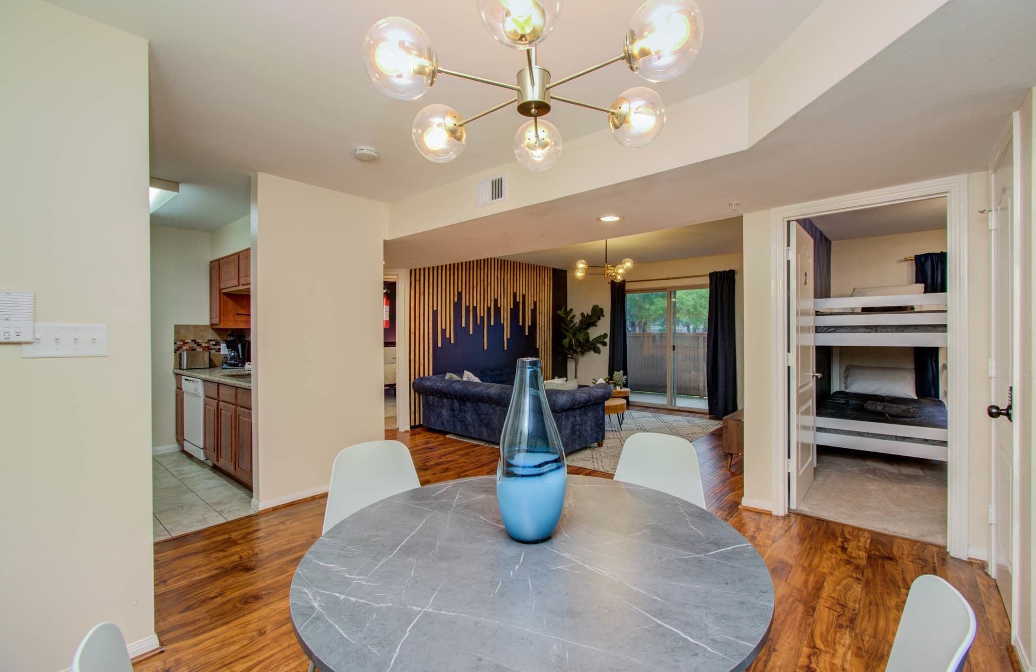 A modern living room with a round marble table, a blue vase, and a chandelier.