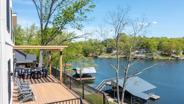 Eine Terrasse mit Sitzgelegenheiten im Freien, einer Pergola und Blick auf einen See mit angestaubten Booten.