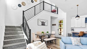 Ein modernes Wohnzimmer mit Treppe, Essbereich und Küche.