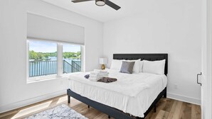 Ein Schlafzimmer mit Bett, Deckenventilator, Fenster mit Blick und Nachttisch mit Lampe.