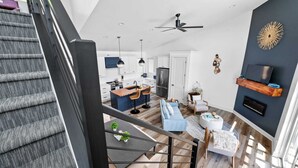 Eine moderne Küche mit einer zentralen Kochinsel, einem Essbereich mit Tisch und Stühlen sowie einer Treppe, die in einen oberen Bereich führt.