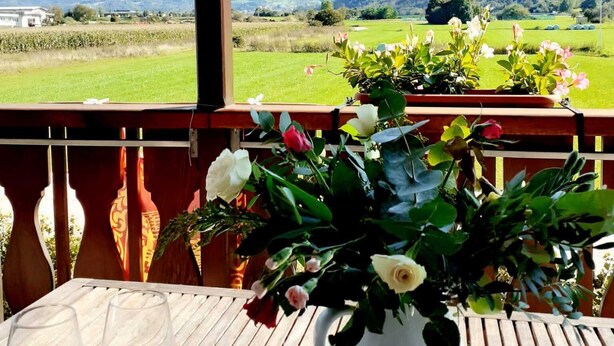 A table with a vase of flowers and two empty wine glasses, overlooking a mountainous landscape. - Spazioso Appartamento Alle Porte Delle Dolomiti (Arten)