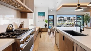 A modern kitchen with a large island, stainless steel appliances, and a view of the outdoor terrace. - Modern Lagoon: Desert Color Lagoon + Beaches (St. George)