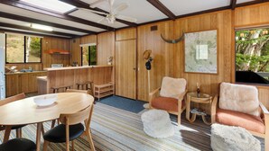 Interior em madeira com uma mesa de jantar, cadeiras, um ventilador de teto e um mapa na parede.