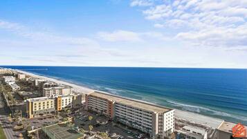 Un hotel costero con varias edificaciones, una playa y un muelle al fondo.