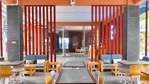 Un área de estar interior moderna con mesas, sillas, un sofá azul y un banco de madera.