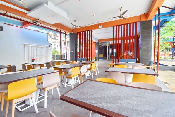 A modern restaurant with multiple tables and chairs, a ceiling fan, and a view of the outside. - OSEIDON HOTEL BORACAY (Boracay Island)
