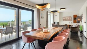 Uma sala de jantar moderna com uma mesa de madeira grande, cadeiras cor-de-rosa e iluminação pendente.