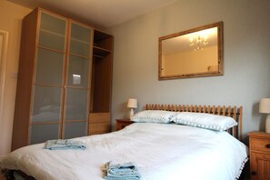 Cozy retreat with a large bed, wooden wardrobe, and classic headboard.