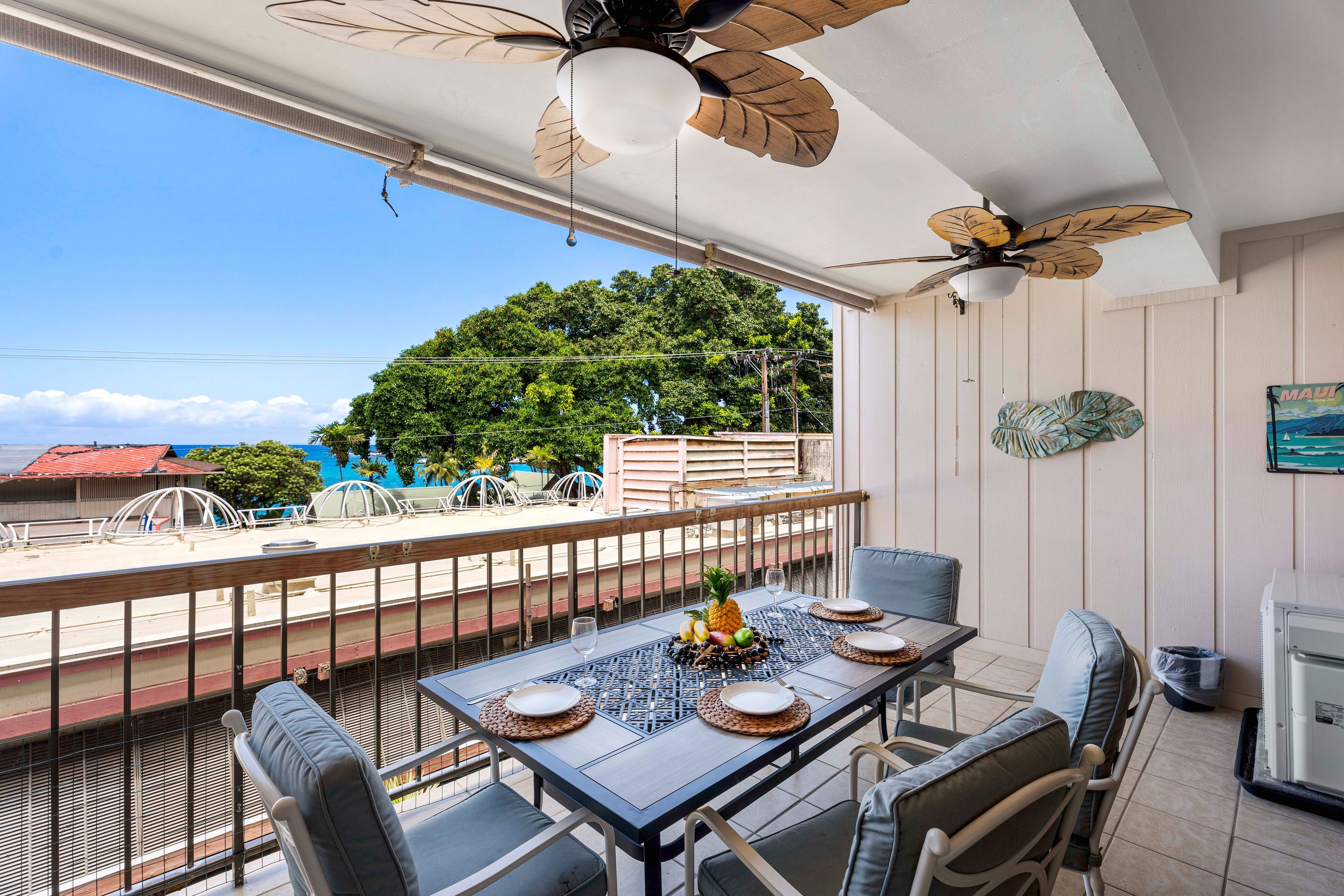 A balcony with a table set for dining, chairs, and a ceiling fan.